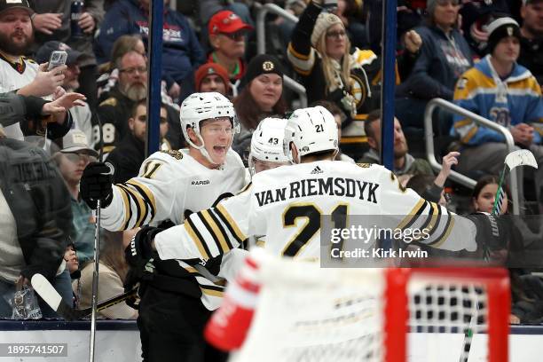 Trent Frederic of the Boston Bruins is congratulated by Danton Heinen and James van Riemsdyk after scoring a goal during the third period of the game...