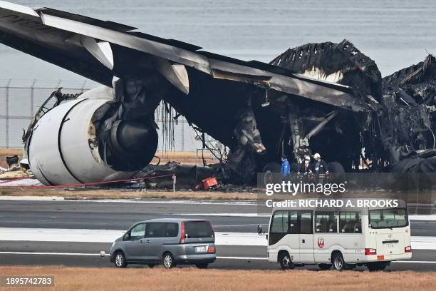 Officials look at the burnt wreckage of a Japan Airlines passenger plane on the tarmac at Tokyo International Airport at Haneda in Tokyo on January 3...