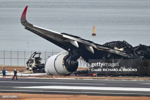 Officials look at the burnt wreckage of a Japan Airlines passenger plane on the tarmac at Tokyo International Airport at Haneda in Tokyo on January 3...