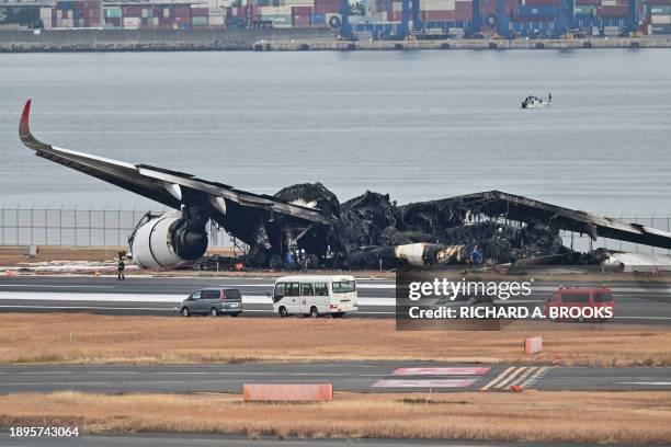 Officials look at the burnt wreckage of a Japan Airlines passenger plane on the tarmac at Tokyo International Airport at Haneda in Tokyo on January 3...