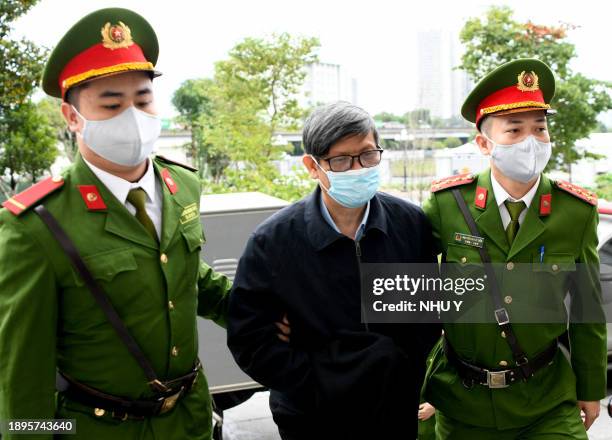 Vietnam's former minister of health Nguyen Thanh Long is led into a court by police for his anti-corruption trial over Covid test kit production...