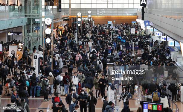 Travellers crowd the check-in area at terminal 2 at Tokyo International Airport at Haneda on January 3 as flight delays on one of the busiest travel...