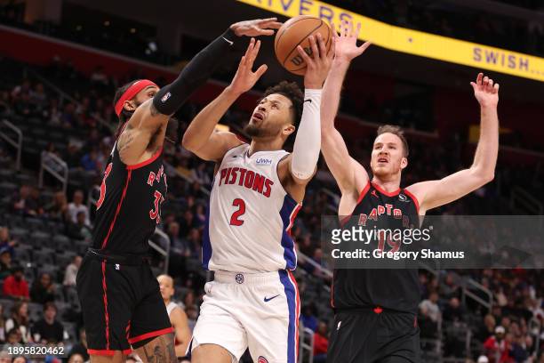 Cade Cunningham of the Detroit Pistons drives to the basket between Gary Trent Jr. #33 and Jakob Poeltl of the Toronto Raptors during the first half...