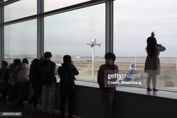 Onlookers in front of the wreckage of a Japan Airlines Co. Aircraft that caught fire following a collision with a smaller plane on the runway at...