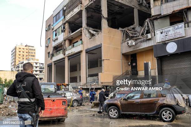 Member of the Lebanese Army Intelligence stands by as municipal workers clean the street by the building that was hit by a drone strike attributed to...