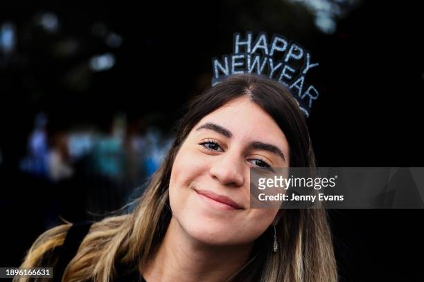 Woman poses for a photo wearing a Happy New Year headpiece on December 31, 2023 in Sydney, Australia. Revellers turned out in large numbers to...
