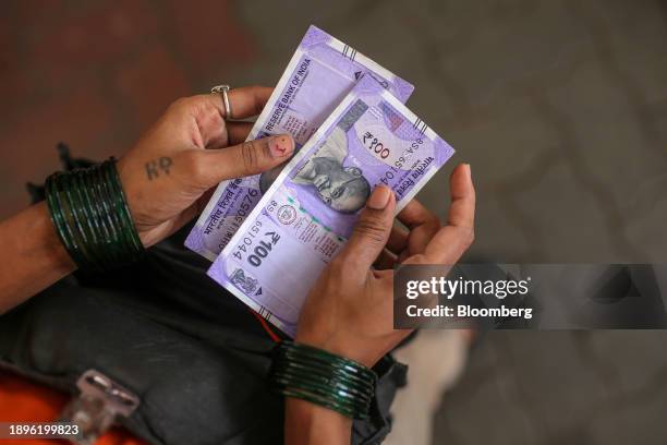 An employee holds one hundred rupee banknotes at an Indian Oil Corp. Gas station in Mumbai, India, on Wednesday, Jan. 3, 2024. A union of truck and...