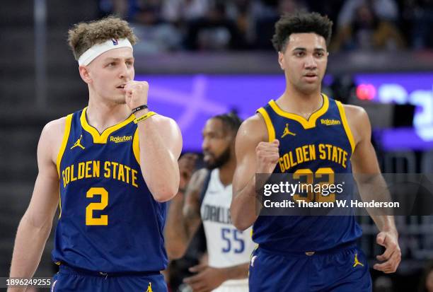 Rookies Brandin Podziemski and Trayce Jackson-Davis of the Golden State Warriors react after teammate Stephen Curry made a three-point shot against...