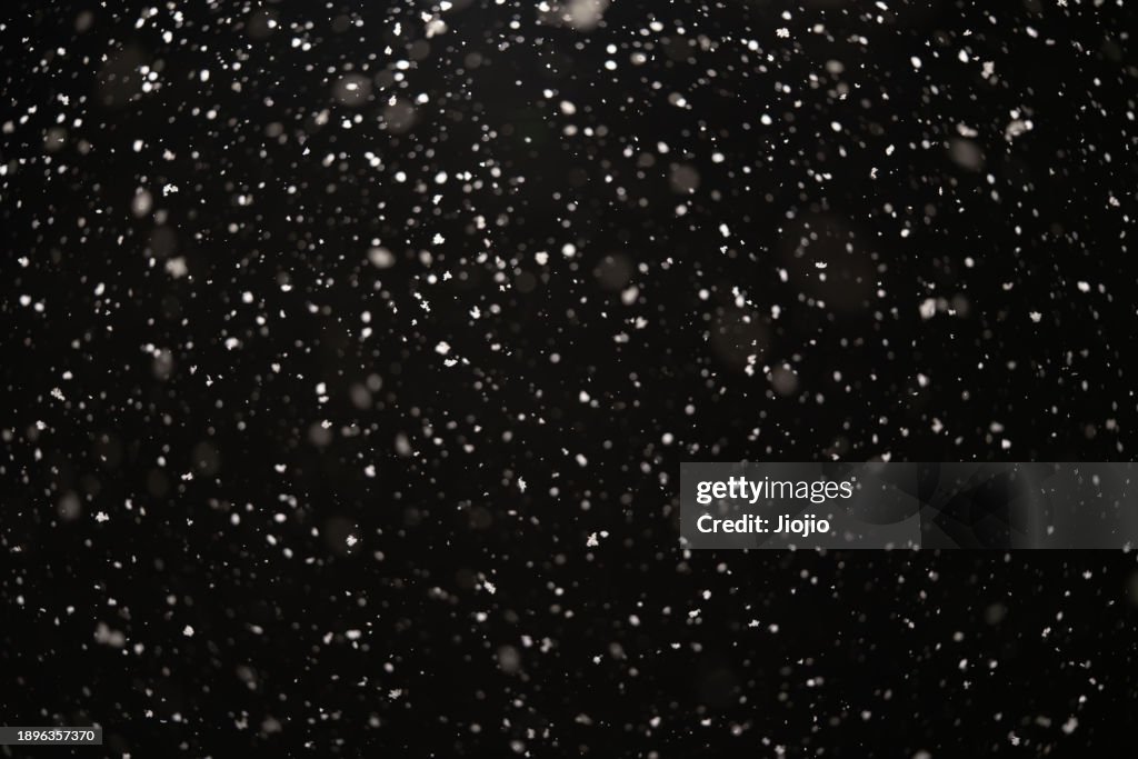 Falling Snowflakes against sky at night