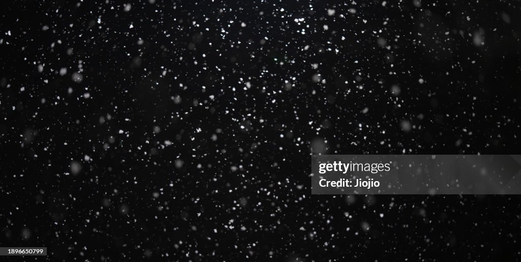Falling Snowflakes against sky at night