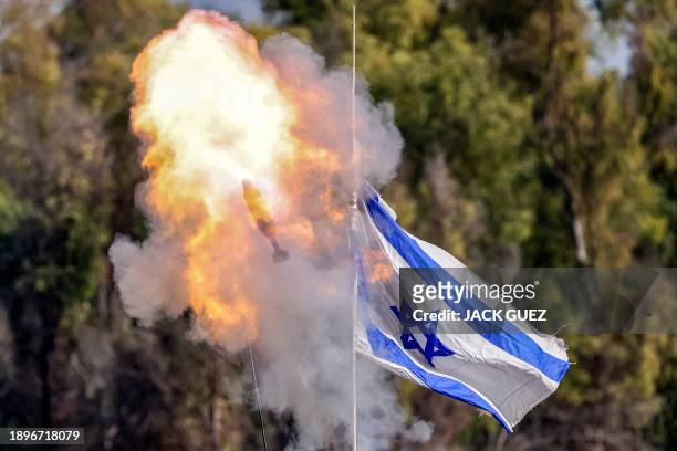Mortar round flies past an Israeli flag waving atop an Israeli armoured vehicle from a position along the border in southern Israel on January 3,...