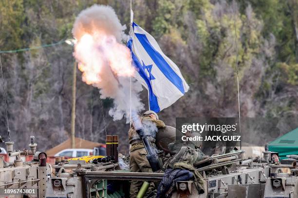 Israeli soldiers cover their ears as they a fire mortar round from an armoured vehicle at a position along the border in southern Israel on January...