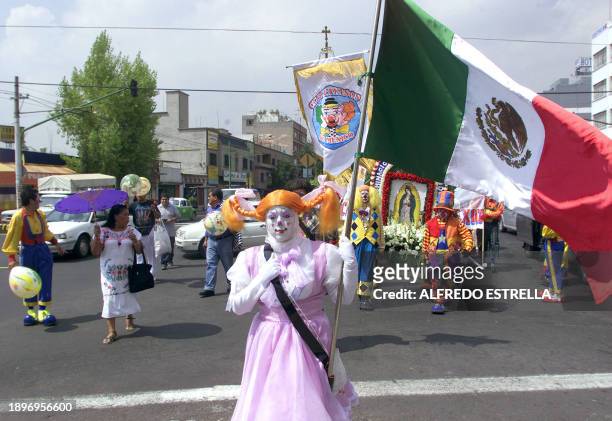 Un mujer disfrazada de payaso, sostiene una bandera de México, durante una peregrinación anual de payasos a la Basilica de Guadalupe, en Ciudad de...