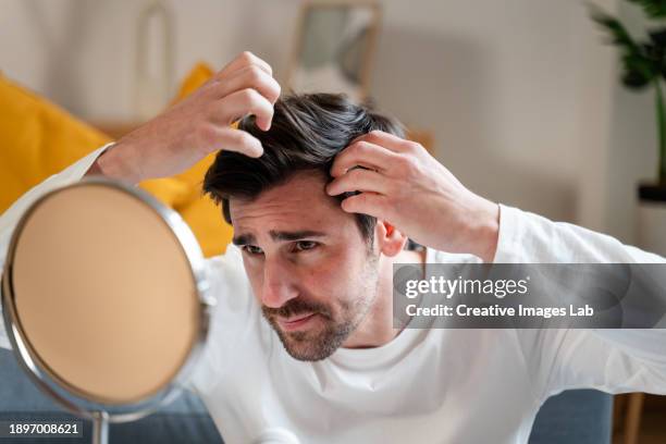 portrait of a young man combing his hair at home. - pérdida de pelo fotografías e imágenes de stock