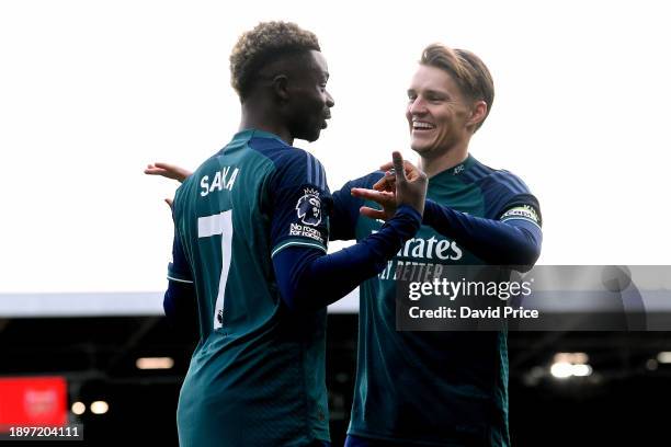 Bukayo Saka of Arsenal celebrates with teammate Martin Odegaard after scoring their team's first goal during the Premier League match between Fulham...