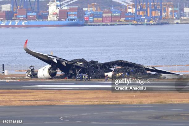 Police and officials inspect the wreckage of Japan Airlines aircraft JAL Flight 516 on the tarmac of Tokyo Haneda Airport on January 3 in Tokyo,...