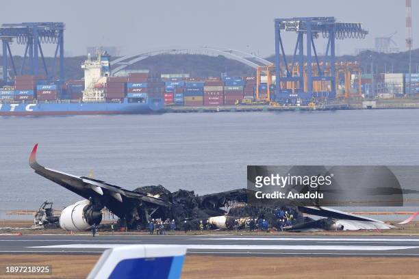 Police and officials inspect the wreckage of Japan Airlines aircraft JAL Flight 516 on the tarmac of Tokyo Haneda Airport on January 3 in Tokyo,...