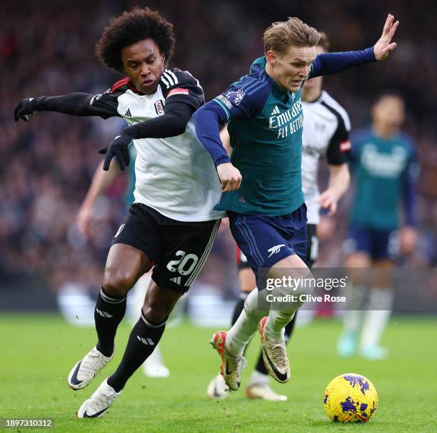 Willian of Fulham and Martin Odegaard of Arsenal battle for possession during the Premier League match between Fulham FC and Arsenal FC at Craven...