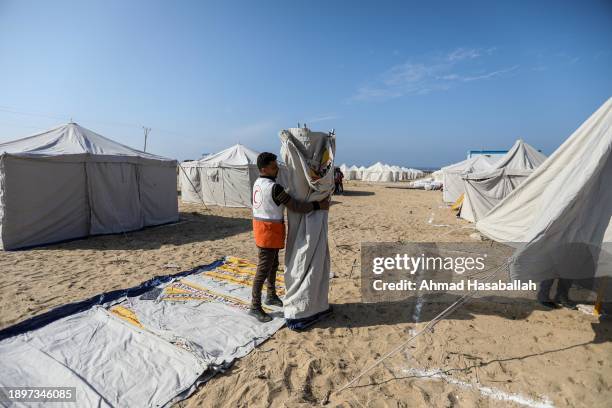 Members of the Egyptian and Palestinian Red Crescent erect tents for Palestinians displaced by the ongoing Israeli attacks on Gaza on December 31,...