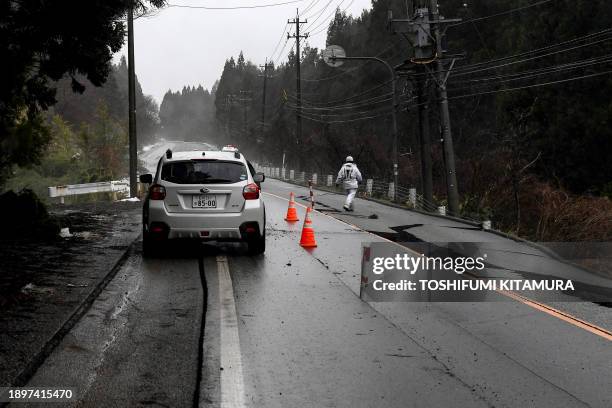 Car rides along a cracked road in Anamizu town, Ishikawa prefecture on January 3 after a major 7.5 magnitude earthquake struck the Noto region in...