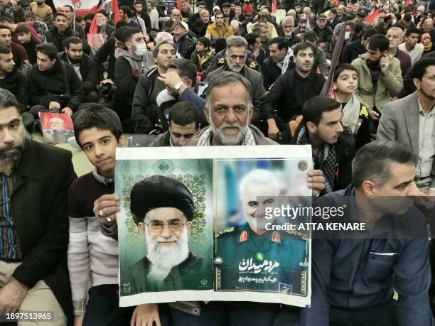 Man holds portraits of Supreme Leader Ayatollah Ali Khamenei and slain top Iranian commander Qasem Soleimani during the ceremonies marking the...