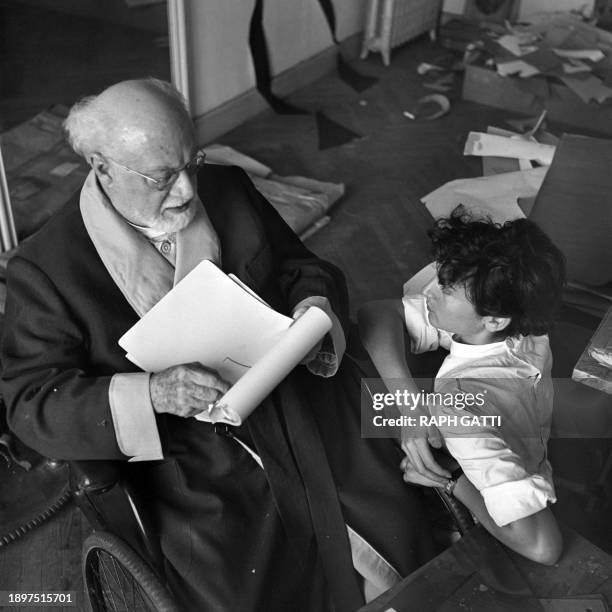 Le peintre et sculpteur français Henri Matisse photographié dans son atelier nicois en 1952 en presence d'une jeune femme.