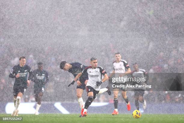 Andreas Pereira of Fulham runs with the ball in a rain storm during the Premier League match between Fulham FC and Arsenal FC at Craven Cottage on...