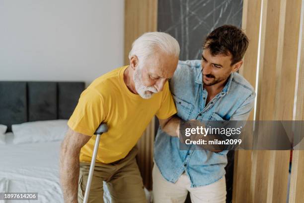 son helping his father - hip stock pictures, royalty-free photos & images