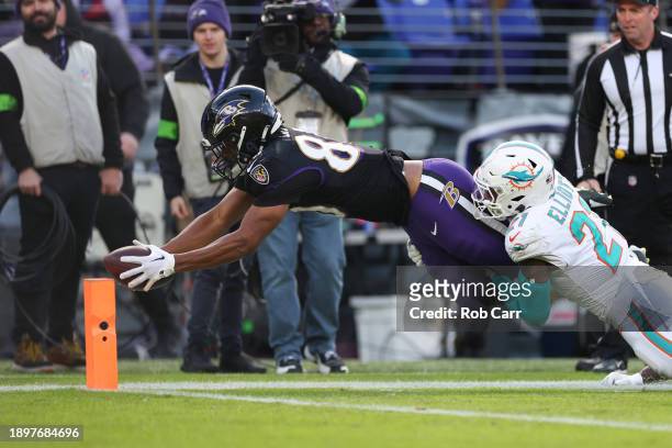 Isaiah Likely of the Baltimore Ravens scores a touchdown past DeShon Elliott of the Miami Dolphins during the second quarter of the game at M&T Bank...