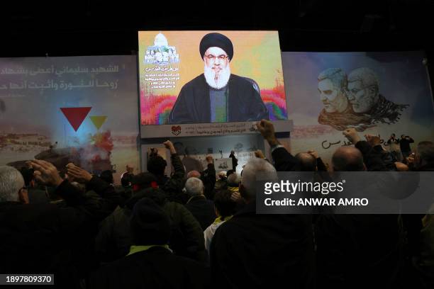 People watch the televised speech of Lebanon's Hezbollah chief Hasan Nasrallah to mark the anniversary of the killing of slain top Iranian commander...
