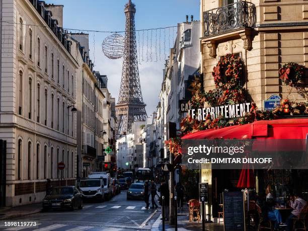 This photograph taken on January 3 shows people sitting at a cafe with the Eiffel Tower in the background in Paris.