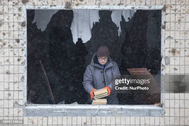 Man is collecting books in the damaged apartment of a residential building that was destroyed by a missile strike in Kyiv, Ukraine, on January 3,...