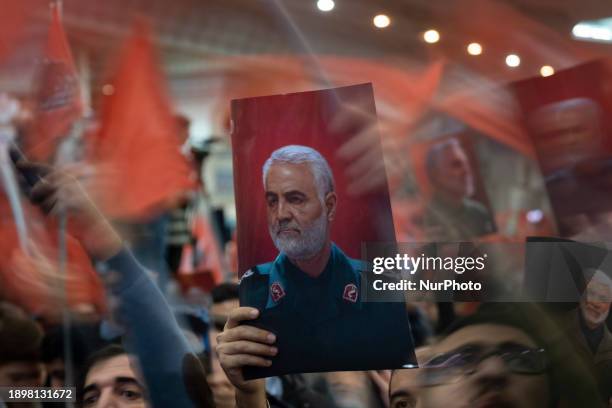 An Iranian man is holding up a portrait of the former commander of the Islamic Revolutionary Guard Corps' Quds Force, Major General Qassem Soleimani,...