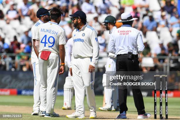 The umpire inspects the pitch as Inia players talk to each other during the second day of the second cricket Test match between South Africa and...