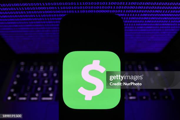 Binary code displayed on a laptop screen and CashApp logo displayed on a phone screen are seen in this illustration photo taken in Krakow, Poland on...