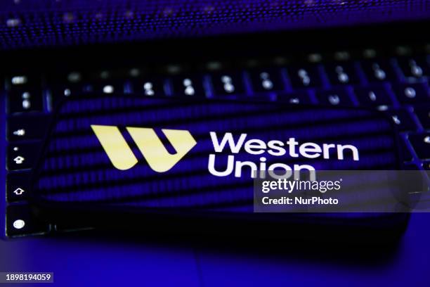 Binary code displayed on a laptop screen and Western Union logo displayed on a phone screen are seen in this illustration photo taken in Krakow,...