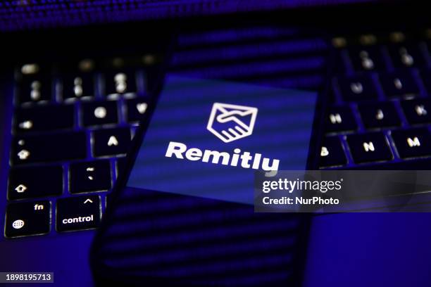 Binary code displayed on a laptop screen and Remity logo displayed on a phone screen are seen in this illustration photo taken in Krakow, Poland on...
