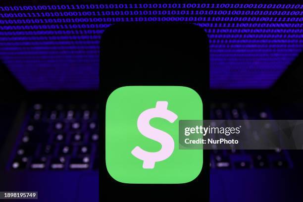 Binary code displayed on a laptop screen and CashApp logo displayed on a phone screen are seen in this illustration photo taken in Krakow, Poland on...