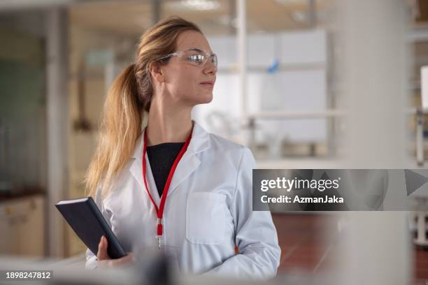 portrait of a caucasian female scientist at the laboratory looking to one side of the lab. - biochemist stock pictures, royalty-free photos & images