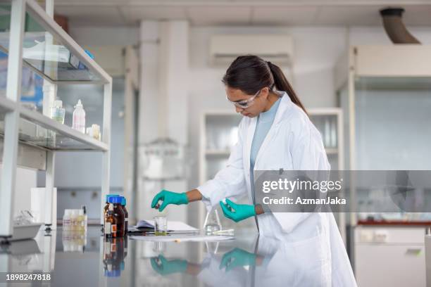 young asian female scientist with protective gloves working with substances at the laboratory - luva vestuário para proteção imagens e fotografias de stock
