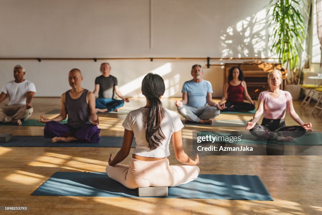Gruppe von multikulturellen Yoga-Teilnehmern sitzt meditierend
