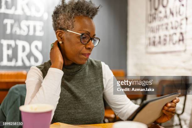 serious mature adult black female working remotely in a london cafe - coffee to go cups stock pictures, royalty-free photos & images