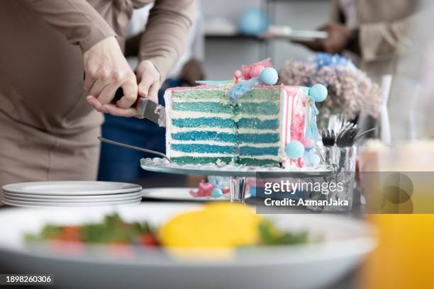 beautiful blue cake with layers on a cake stand being cut at a gender reveal party - gender reveal stock pictures, royalty-free photos & images