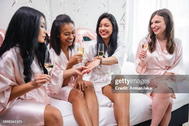 un gruppo di diverse amiche che ammirano l'anello di fidanzamento della loro migliore amica a una festa di addio al nubilato - black women engagement rings foto e immagini stock