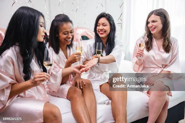 a group of diverse female friends admiring the engagement ring of their best friend at a bachelorette party - showing appreciation stock pictures, royalty-free photos & images