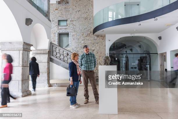 senior caucasian couple standing by a statue in a history museum and looking at it - kinetic sculpture stock pictures, royalty-free photos & images