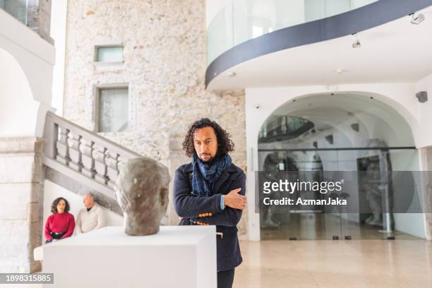 adult black male museum visitor admiring a bust in a history museum - bust museum imagens e fotografias de stock