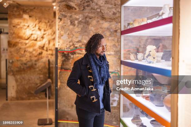 visiteur du musée masculin noir adulte admirant les vieux artefacts du musée d’histoire - musée historique photos et images de collection