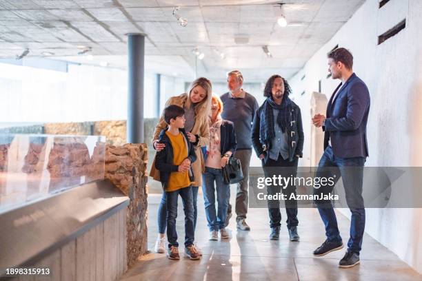 eine gruppe unterschiedlicher menschen, die eine tour durch das geschichtsmuseum mit einem kaukasischen männlichen führer machen - museumswärter stock-fotos und bilder