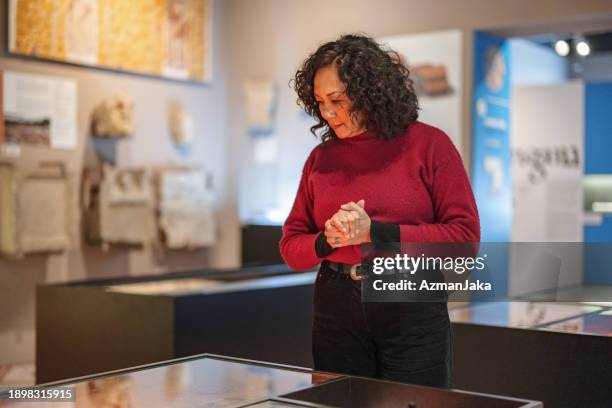 femme caucasienne adulte aux cheveux bouclés visitant un musée d’histoire et regardant des artefacts - musée historique photos et images de collection